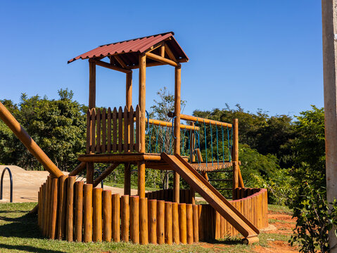 Parque infantil de madeira na grama em um parque p&uacute;blico arborizado / Wooden playground on the grass in a wooded public park