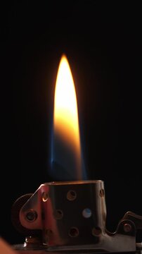 Igniting gasoline lighter on black background. Vertical footage