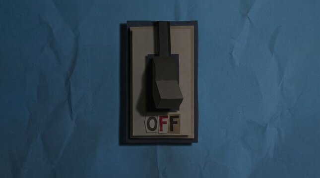 Minimalist paper switch on crumpled blue paper background with word off visible, muted lighting and shadow creating moody, tactile still life
