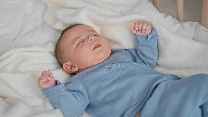 Hispanic newborn baby lying in crib on white blanket raising hand and kicking foot in studio  calm comfort bonding. © Krakenimages.com
