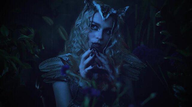 fantasy character fashion model posing in dark night forest grass trees moon light. sharp claws black nails evil gothic fairy woman owl, bird costume. sexy face eyes lips fairy tale elf girl art video