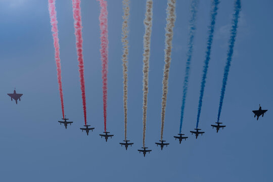 Air show of July 14. 9 Alphajets of the patrol of France in big nine formation and 2 mirage 20000 Ukrainian Air Force flying above the district of La Defense with blue sky and sun background