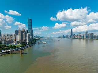 Naklejka premium A scenic view of the modern skyline and the river in Wuhan China during a bright sunny day with blue sky and white clouds