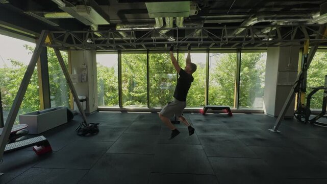 Man training pull ups doing crossfit in modern gym