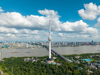 Obraz premium A high aerial view showing the tall television tower standing above the lush green park and the river bridge in the city of Wuhan China