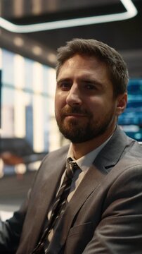 Vertical Shot of a Confident Businessman Trader Working on Stock Market Strategy in a Modern Asset Management Firm. Broker Turns and Lookis at Camera.