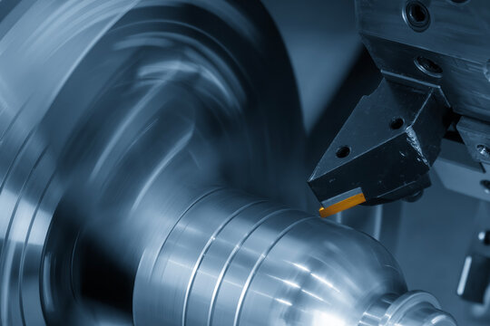 Macro shot of a special purpose chip insert on a lathe tool cutting a metal shaft part.