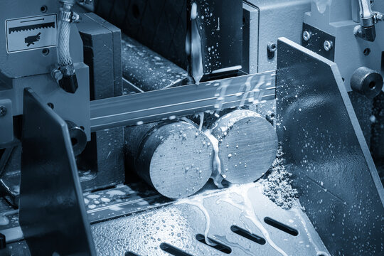 Industrial bandsaw machine performing a material preparation process cutting a metal rod.