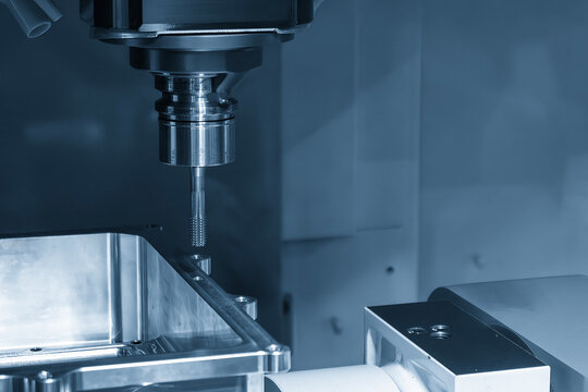 High-precision CNC milling machine performing a thread making process on an aluminum case part with a tapping tool.
