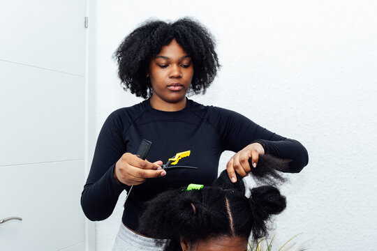 Professional hairstylist preparing black person's afro hair for braids