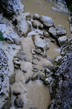 Aerial view of muddy stream flowing through rocky creek bed