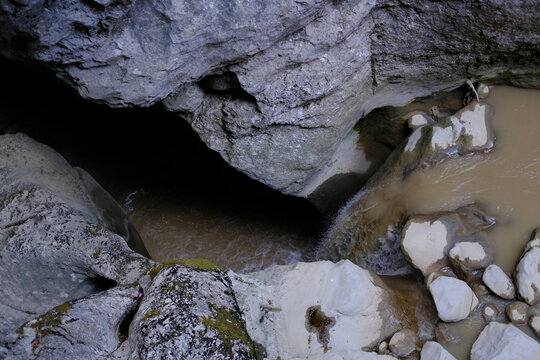 Aerial view of muddy stream flowing through rocky creek bed