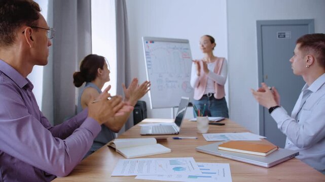 Business team applauding a female colleague after her successful project presentation in a modern office