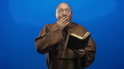 Fototapeta premium Man holding bible and clutching cross with hand, sometimes covering mouth in a studio portrait session; reverence contemplation.