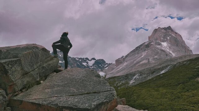Hiker looking up at the mountain peaks and clouds surrounding her at the Britanico viewpoint, Torres del Paine, Patagonia, Chile