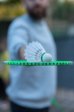 Close-up of a shuttlecock balanced on a badminton racket, with a blurred background, perfect for sports and fitness concepts.