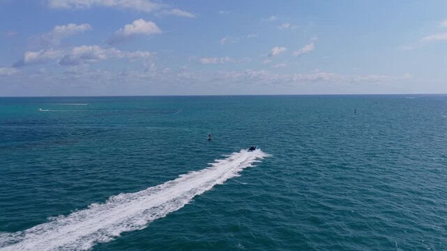 Motorboat enters marina while luxury yacht waits beside boat dock. Sea reflects bright summer sun. Yacht, boat, sea and luxury invite relaxing boating, travel and unforgettable vacation