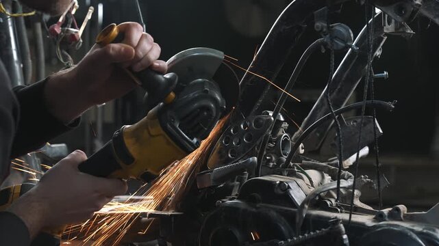 An engineer in a garage is modifying a motorcycle, sawing and trimming off excess frame elements with a circular saw.