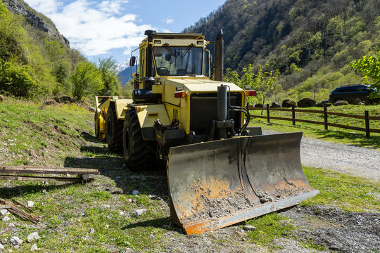 Yellow heavy duty wheeled tractor with a blade in the mountains