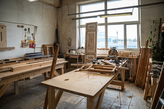 Spacious organized restoration workshop interior featuring worktable, instruments, tools and window, carpentry workroom filled with wooden materials and professional equipment for craftsmanship.