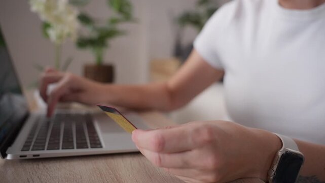 Happy woman browsing online stores with laptop while preparing for secure purchase. Bank card on table, smart shopping, price comparison and saving money through online deals.