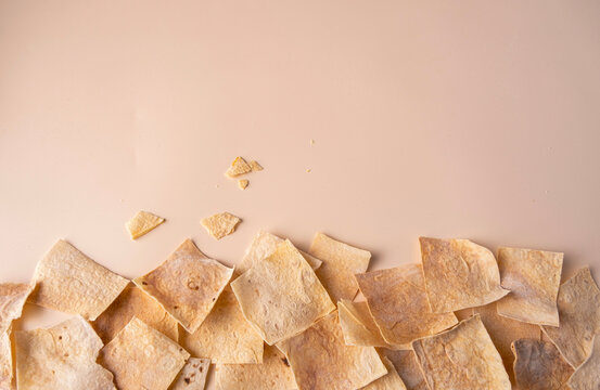 Square Armenian lavash chips scattered on a beige background, space for text