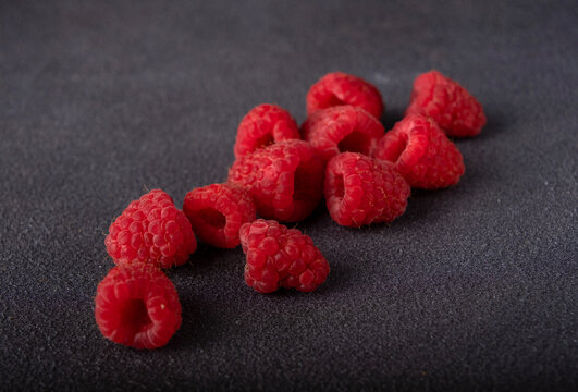 red raspberries scattered on dark background, selective focus