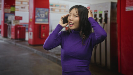 Woman holding smartphone to ear, smiling with clenched fist in celebration at street gas station  triumph joy relief. © Krakenimages.com