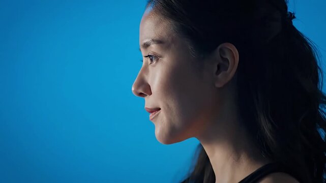 A serene profile portrait of a young woman against a blue backdrop.