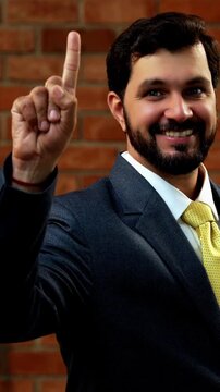 Showing numbers using fingers with confident expression, Indian Asian bearded ceo businessman in formal corporate attire demonstrating finger counting while standing in cozy office against brick wall