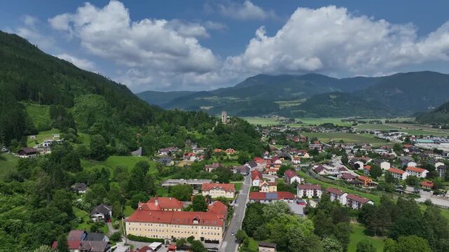 Summer drone footage showing medieval Friesach, old fortified walls, rooftops, towers, hills, serene atmosphere, warm daylight, gentle cinematic motion