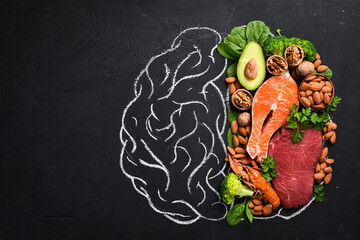 Fototapeta premium Concept of healthy food for the brain: fish, meat, nuts, vegetables and greens. Brain drawing with chalk on a blackboard. Top view. On a black background.