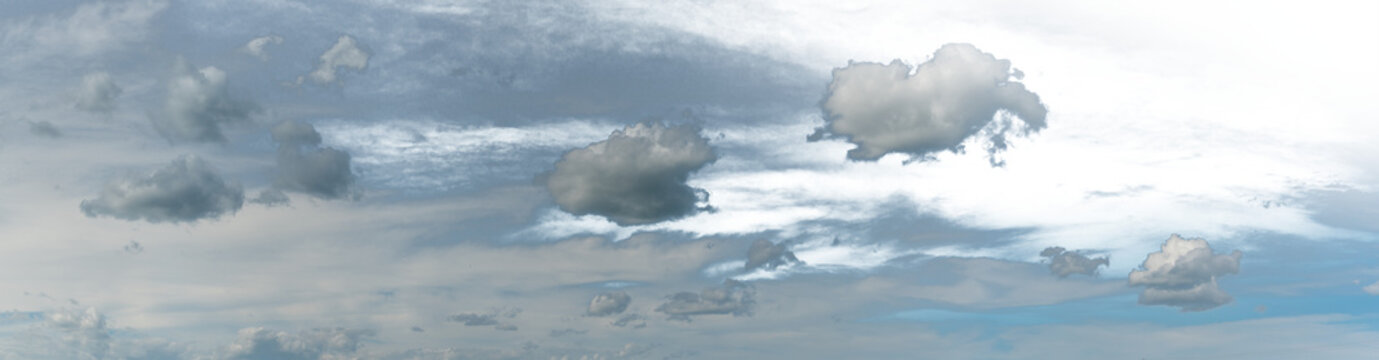 Panorama of a light blue sky with white clouds. Portions of the sky are transparent.
