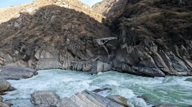 An old bridge opposite the landscape of Tiger Leaping Gorge in Yunnan province of China. Scenic spot where a tiger is said to have leaped across the river, thus giving the gorge its name.