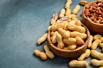 Two wooden bowls with peeled peanuts and peanuts in the shell. Nuts close-up. © Yaruniv-Studio