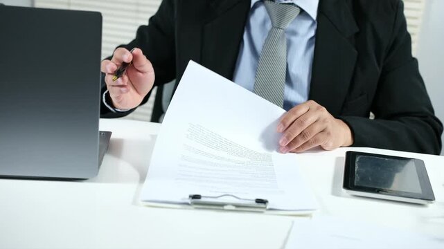 Young business man working at desk. document check concept with a businessman open a document sheet and using pen to write and checking
