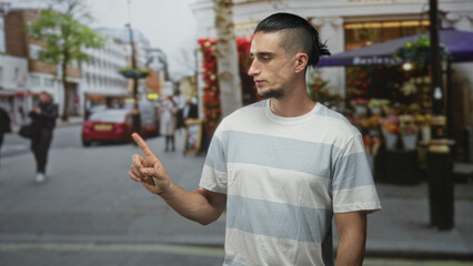Obraz premium Man gazes sideways at flower stall, striped t shirt and bare forearm visible, standing on a busy street; quiet contemplation.