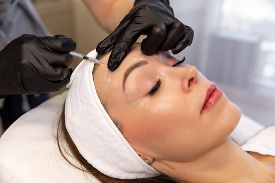 A cosmetologist provides facial rejuvenation injections for middle-aged women, aesthetic medicine and professional care concept. Anti-aging treatment and face lift in cosmetology clinic.