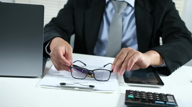 An office worker puts his glasses on his desk and stretches his arms. The concept of fatigue from working in front of a laptop. Stress and fatigue under pressure.