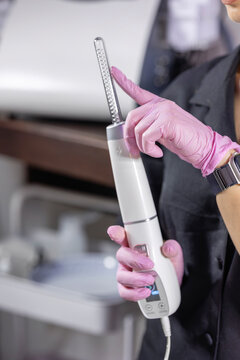 Close-up of a cosmetic physician demonstrating a high frequency wand with a glass electrode used for professional facial skincare and noninvasive cosmetic treatments.