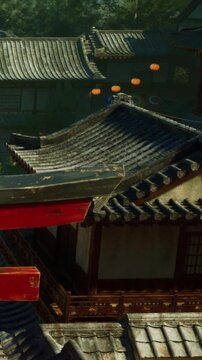 A red structure is in the foreground with dark layered roofs of temples in the background. Lanterns are hanging, and there is a sense of an historical setting in nature.