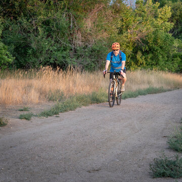Senior male cyclist is riding a toruring bike on a gravel road in Fort Collins in northern Colorado, late summer scenery