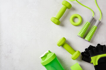 Naklejka premium Assorted green sport equipment and workout accessories on the right side of a textured gray background with copy space. Flat lay.