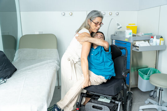 Caregiver helping man with disability transferring from wheelchair