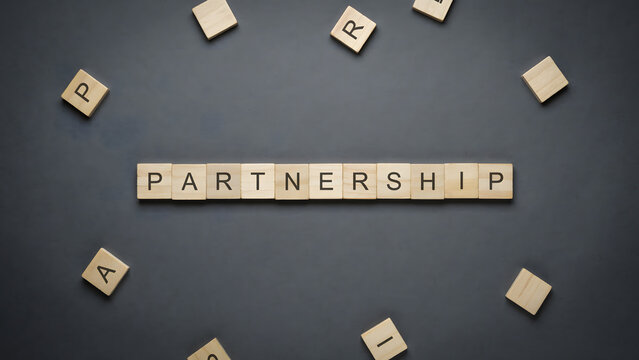 Wooden letter blocks spelling the word partnership on a dark background