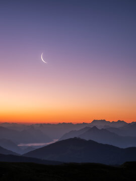 Crescent moon over layered mountain silhouettes, Central Switzerland