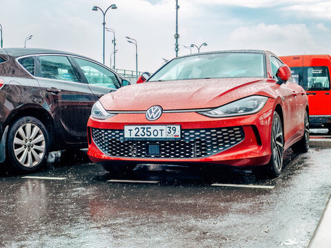 city parking lot on a rainy day and bright red Volkswagen Lamando car