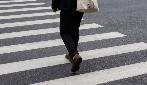 Person with white bag on his back walking on a crosswalk, determined, crossing the street on a pedestrian crossing
