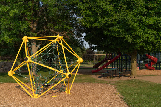 Geodesic dome climbing structure at a park playground on summer morning