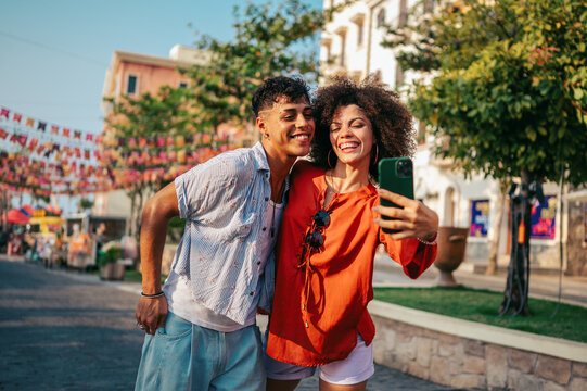 Young people capturing the vibrant urban tropical vibe, happily taking a selfie on a colorful street